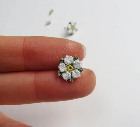 tiny micro crochet white rose flower held on two fingers
