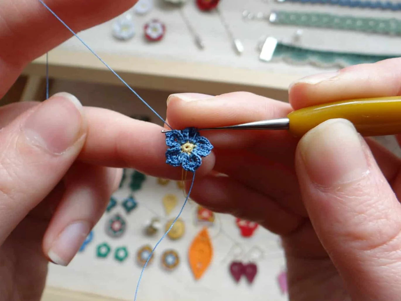 tiny micro crochet forget me not flower being crocheted with hook in hands